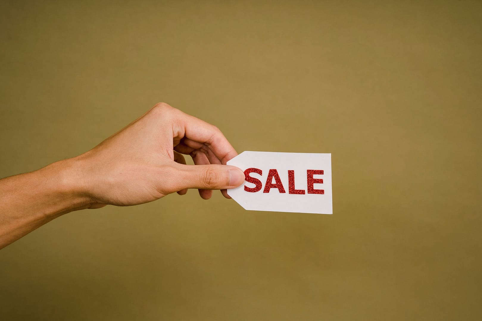 A hand holding a tag with the word 'sale'. A professional copywriting service will help your business sales.